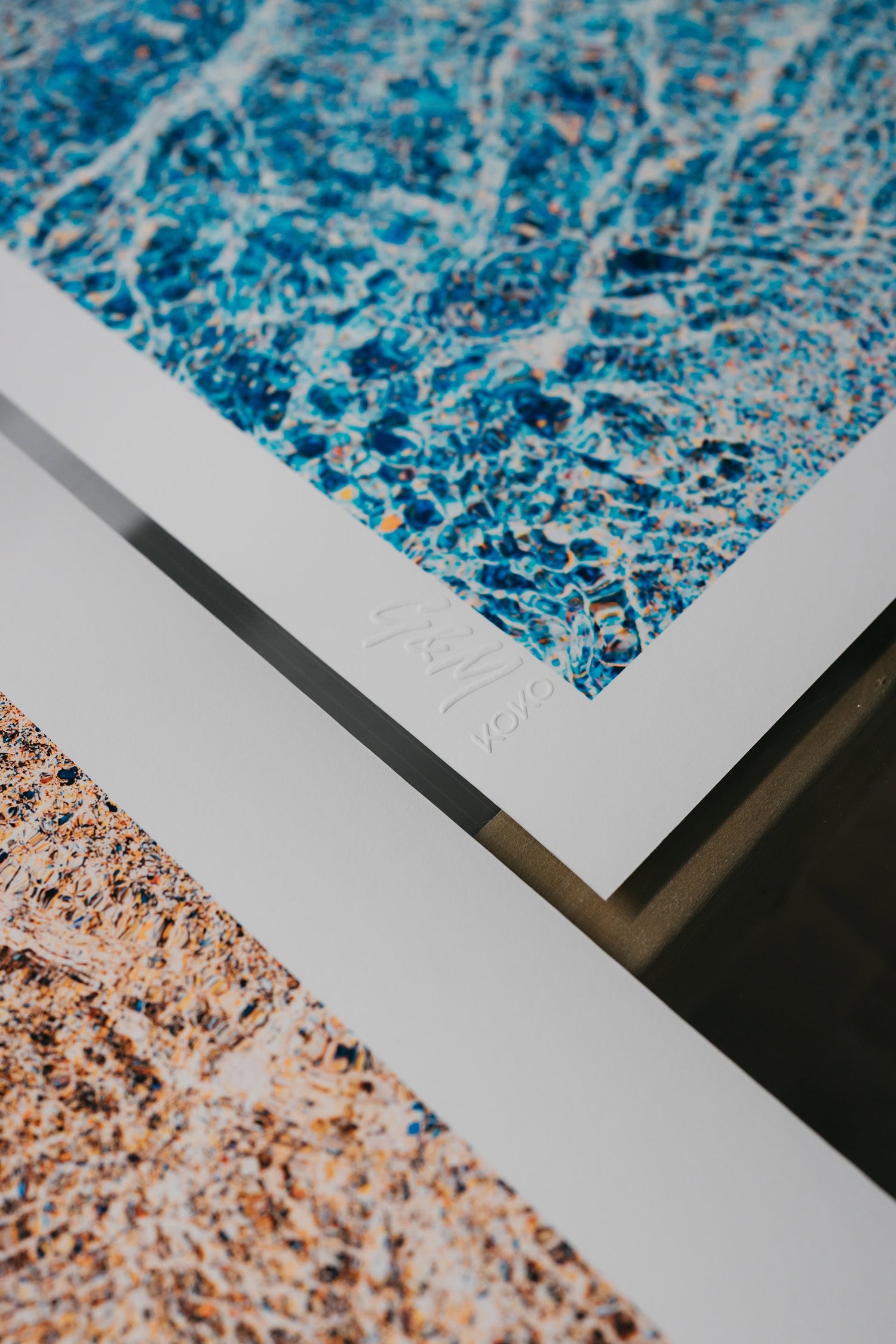 close up of 2 different KOKO Studio ocean fine art prints in azure blues and golden sand colours