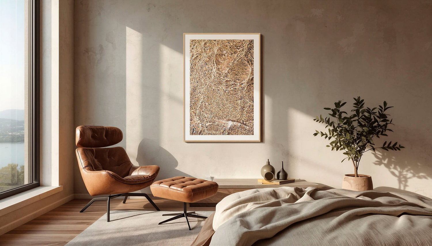 Modern bedroom with a brown leather chair, ottoman, and framed fine art print of abstract water and light reflections taken in Cornwall on the wall.